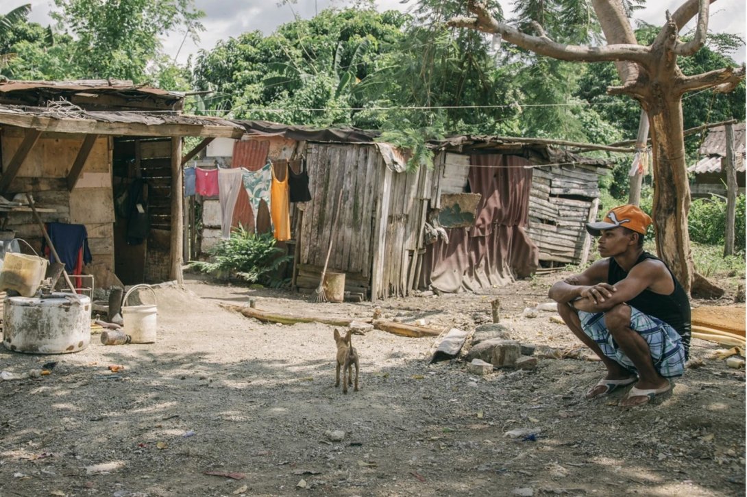 Joven cubano junto a una vivienda en estado crítico. Foto de Theo McInnes.