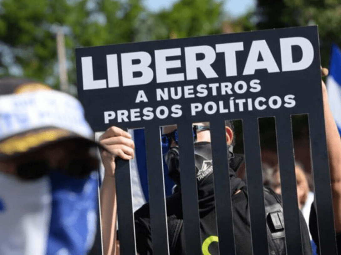 Personas manifestándose alzan un cartel por la libertad de los presos políticos en Nicaragua.
