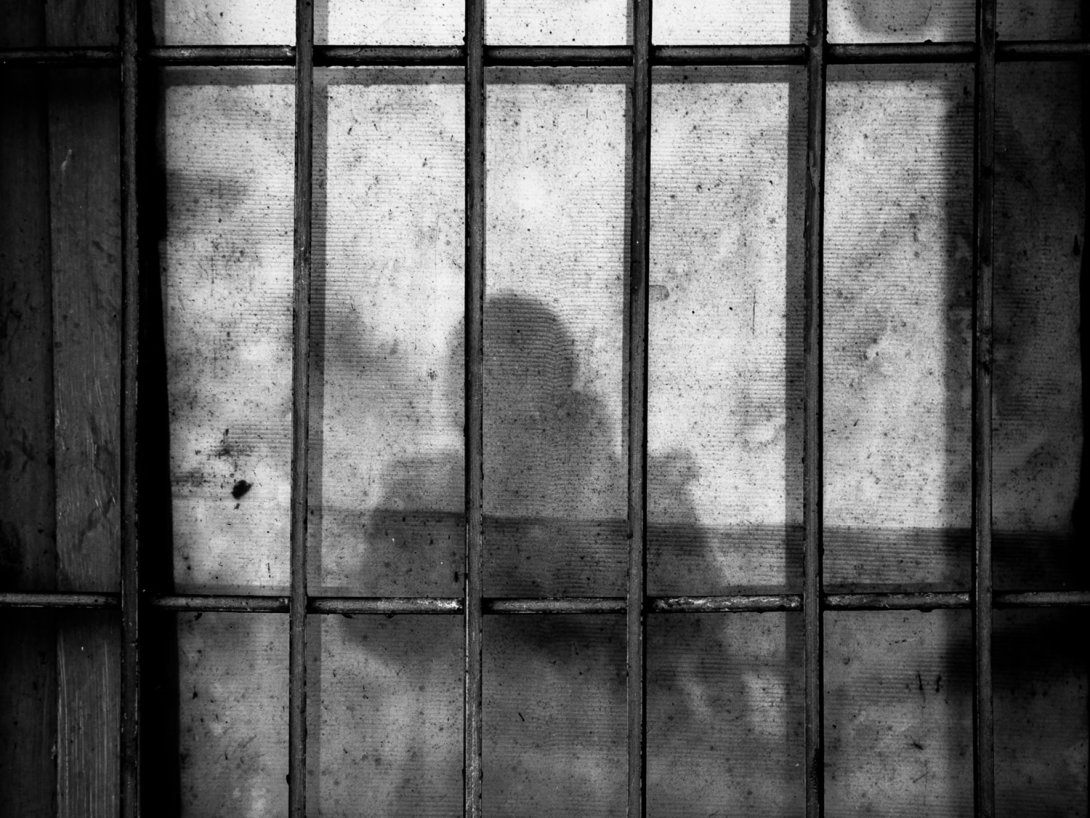 Dibujo de prisión con sombra de una persona detrás de las rejas