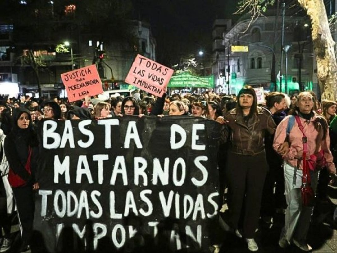 Multitud de mujeres en una marcha nocturna sostienen pancartas con frases como “Basta de matarnos”.