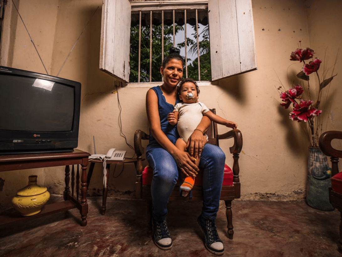 Madre sentada sosteniendo a su hijo.