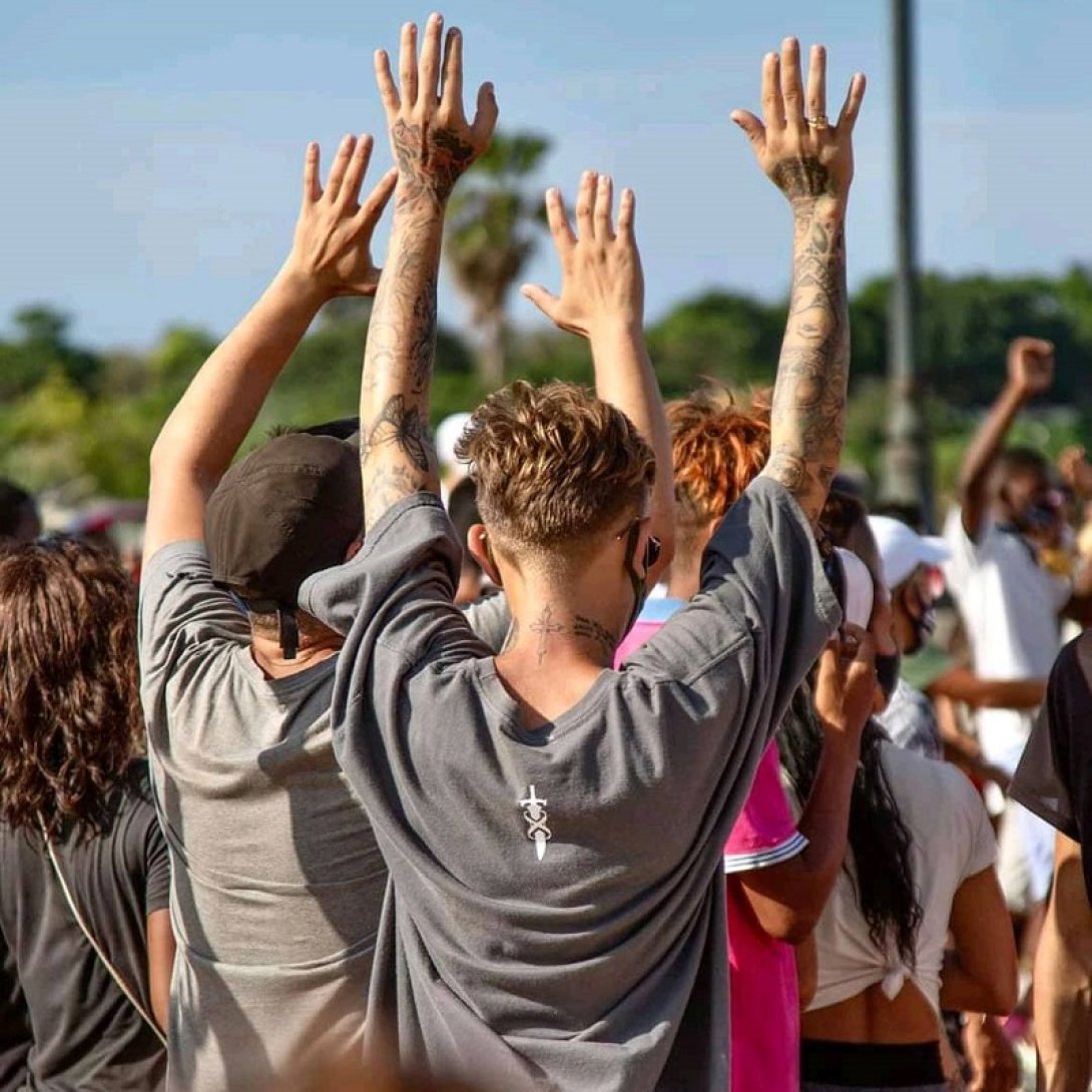 Jóvenes manifestantes cubanos con brazos levantados ante los represores.