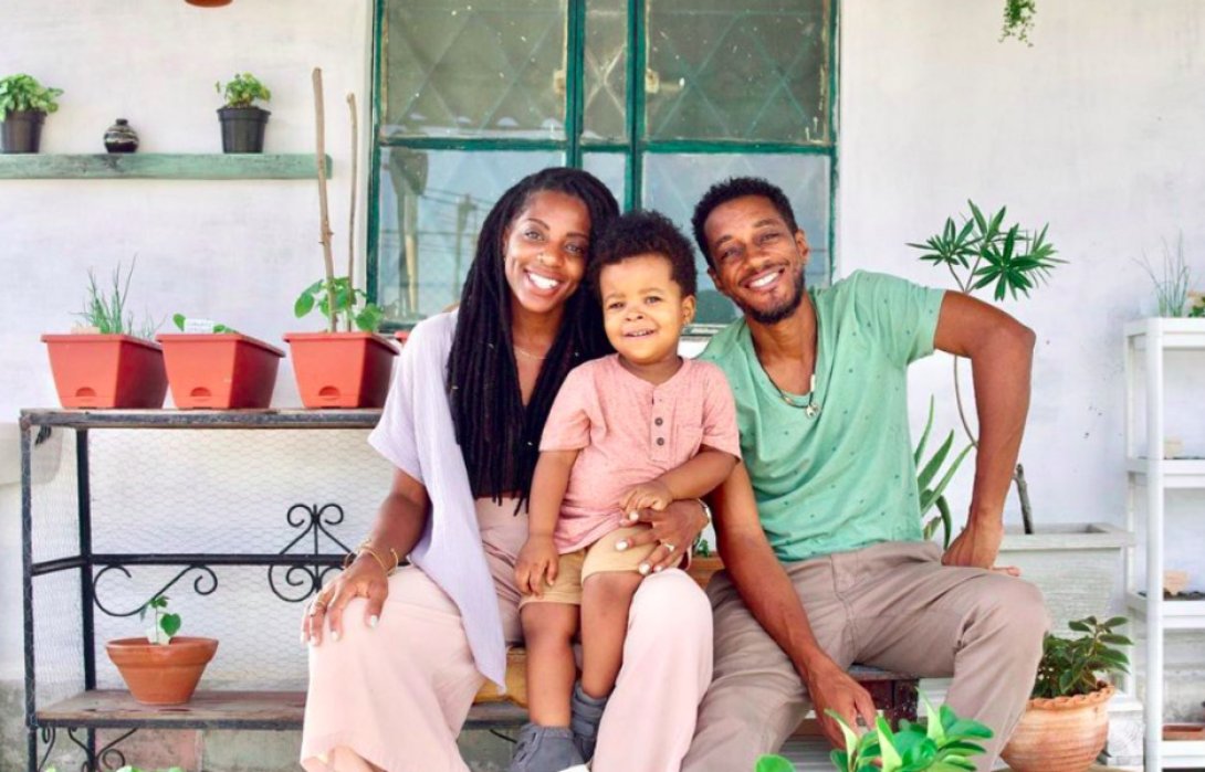 Familia sonriendo con un bebé al centro.
