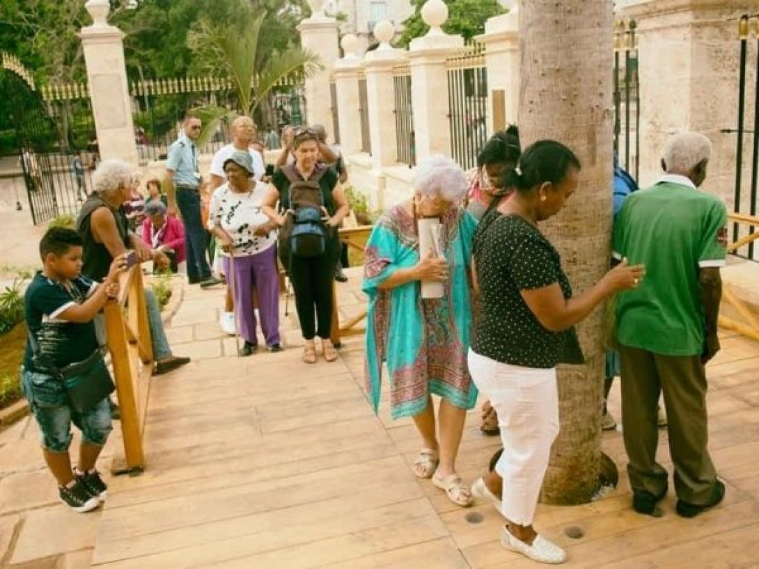 Personas dando las tres vueltas a la ceiba del Templete en La Habana.