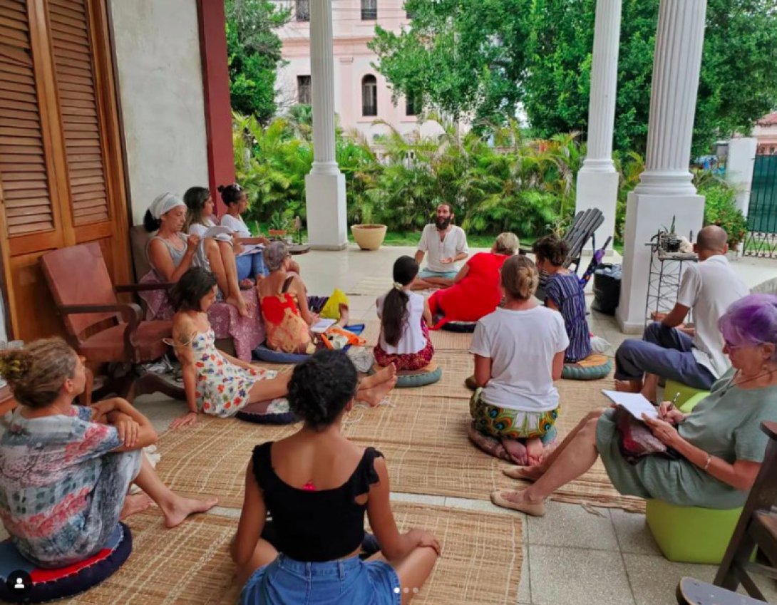 Personas sentadas en el piso reciben una clase.