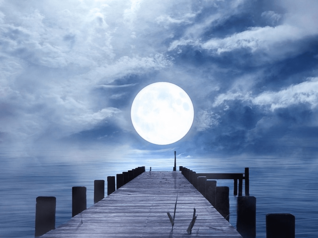 Luna llena sobre el agua al final de un muelle. 