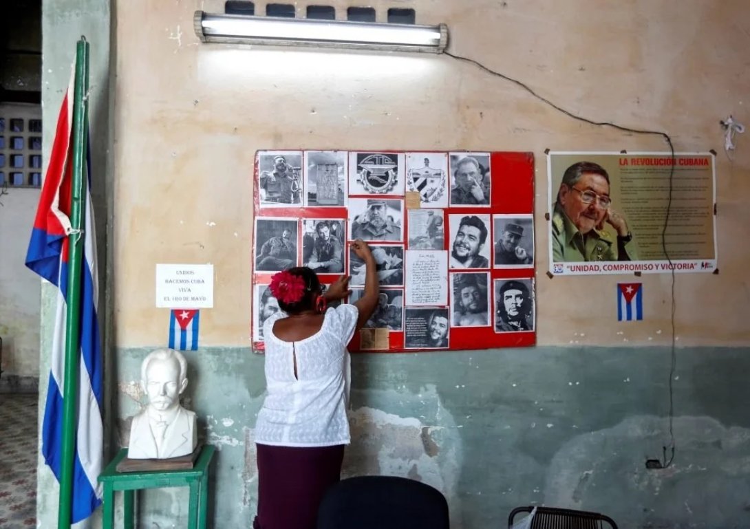 Una mujer cubana arregla el mural político de su trabajo.