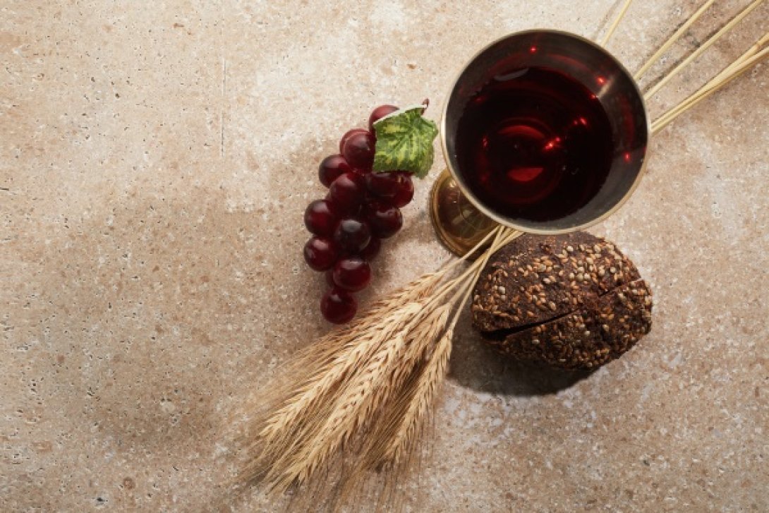 Copa de vino, racimos de uva, y espigas de trigo.