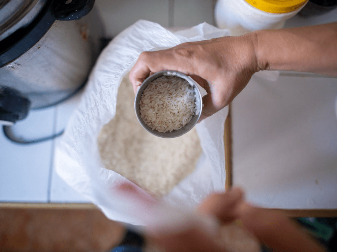 Manos extrayendo arroz de un saco.