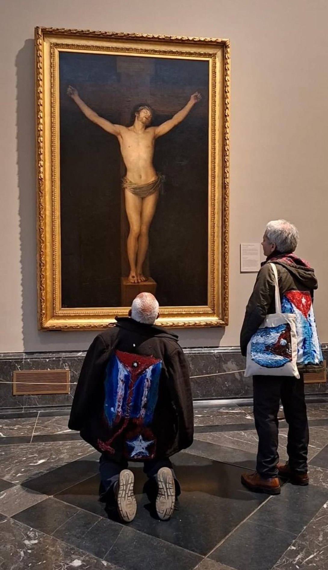 Performance "Mi bandera", de artista cubano exiliado Rafael Vilches, junto al artivista Rigoberto Carceller. Frente al cuadro "Cristo crucificado" (1780) de Francisco de Goya, en el Museo del Prado (23 de marzo de 2026). Foto de Ana Rosa Díaz Naranjo.