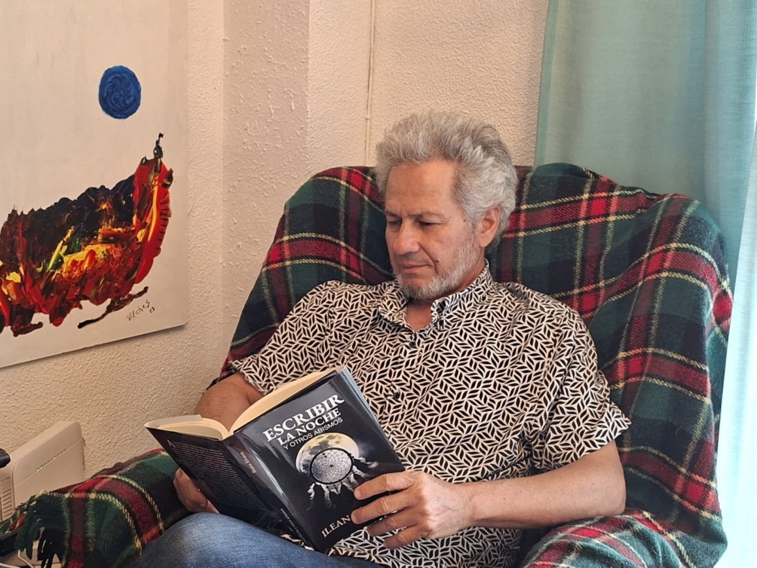 El poeta y artista visual Rafael Vilches leyendo el libro "Escribir la noche y otros abismos" (2024) de Ileana Álvarez. Foto: Ana Rosa Díaz.