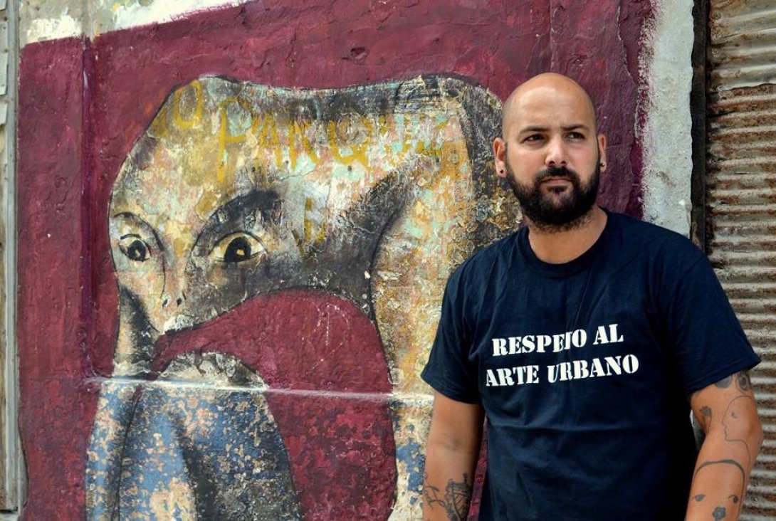 Grafitero cubano Yulier P. junto a una de sus obras en La Habana