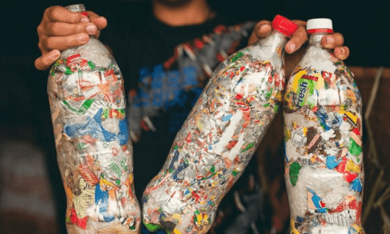 Niño mostrando varias botellas plásticas convertidas en ecoladrillos.