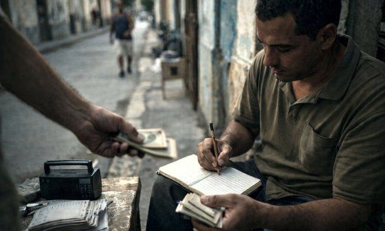Escena inspirada en el juego de la bolita en los barrios de Cuba. Alguien hace una apuesta y un apuntador recoge el dinero.