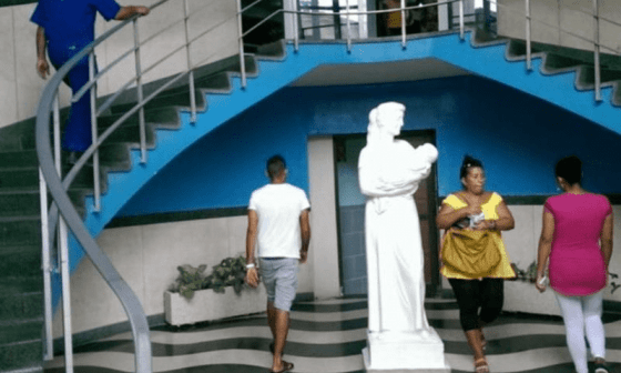 Persona transitando alrededor de la escultura a las madres en el salón del Hospital Hijas de Galicia, La Habana.