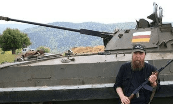 Dugin portando un arma recostado a un tanque de guerra.