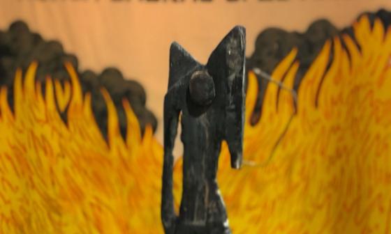 Detalle de escultura de Luis Manuel Otero de la serie "Los héroes no pesan" con obra del colectivo Mujercitas al fondo. 