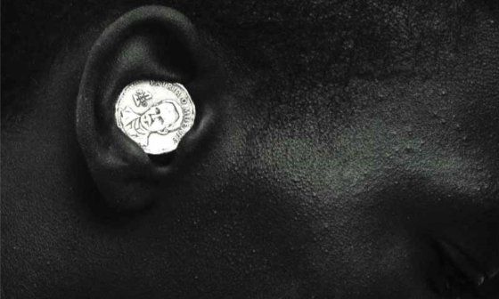 Niño negro con moneda de 1 peso en la oreja. Foto país de píxeles