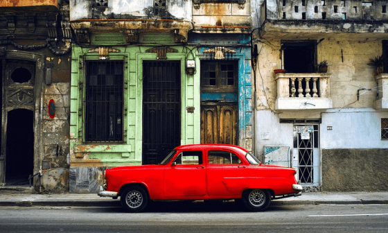 Auto antiguo parqueado frente a edificios viejos en La Habana, Cuba.