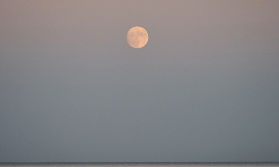 Luna llena sobre el mar en la tarde.