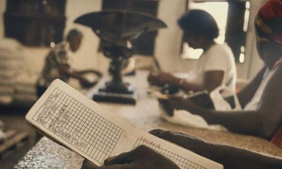 Mano de un consumidor sostiene su libreta de abastecimiento en una bodega cubana, mientras espera el pesaje de productos normados.