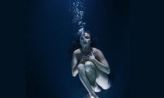 Mujer desnuda sumergida en el agua.