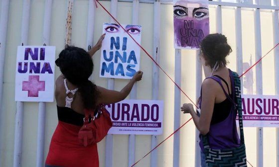 Mujeres pegando feministas en la pared carteles.