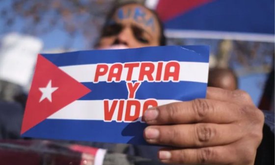 Cubana sosteniendo una bandera cubana con el lema "Patria y Vida".