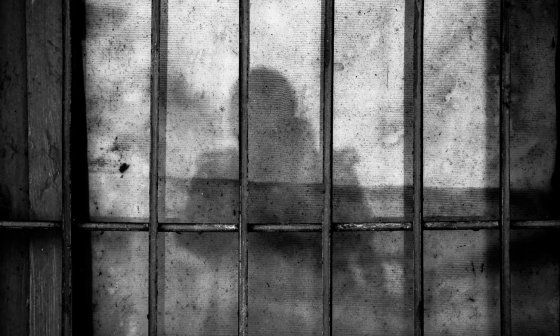 Dibujo de prisión con sombra de una persona detrás de las rejas
