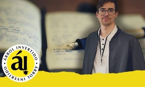 Retrato de Senén Alonso Alum, periodista y editor vinculado a la revista Árbol Invertido, de pie con mochila y camiseta oscura, sobre un fondo difuminado de cuadernos manuscritos.