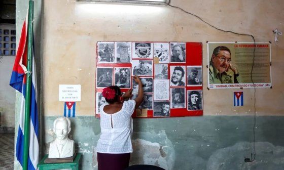 Una mujer cubana arregla el mural político de su trabajo.