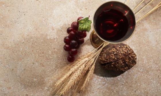 Copa de vino, racimos de uva, y espigas de trigo.