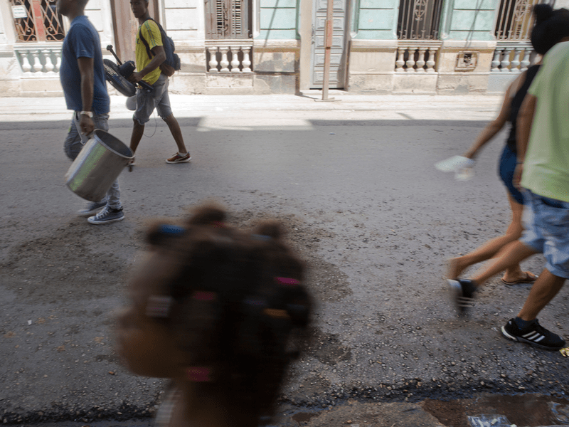 Personas (desenfocadas) caminan en la calle. En primer plano: la cabeza de una niña pequeña.