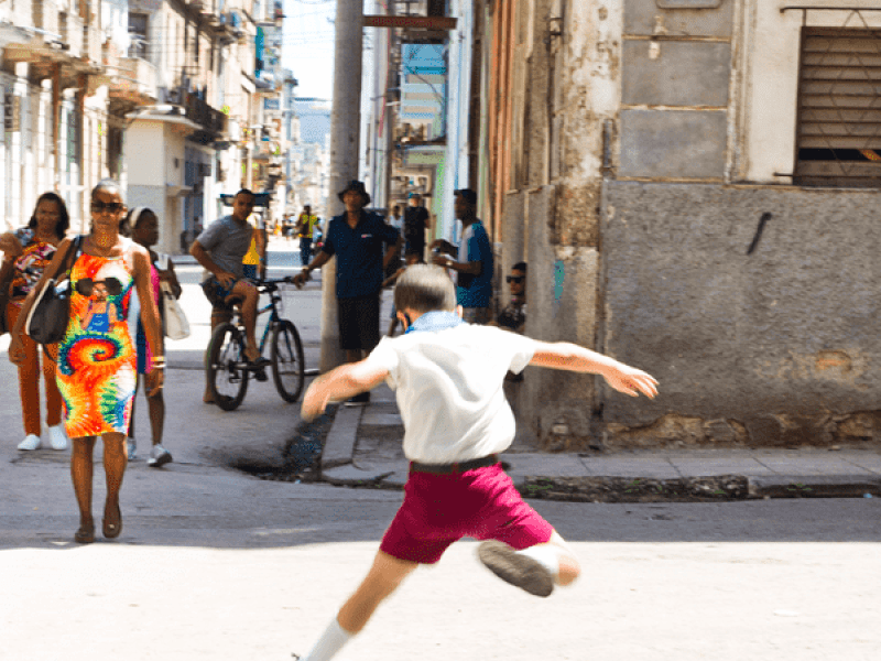 Niño salta sobre un charco de agua en la calle. 