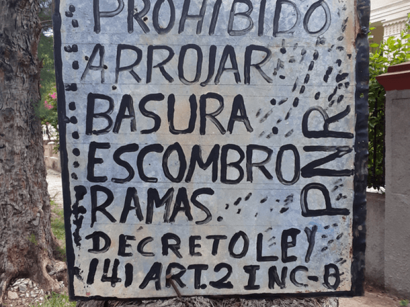 Cartel en un árbol: "Prohibido arrojar basura, escombro..."