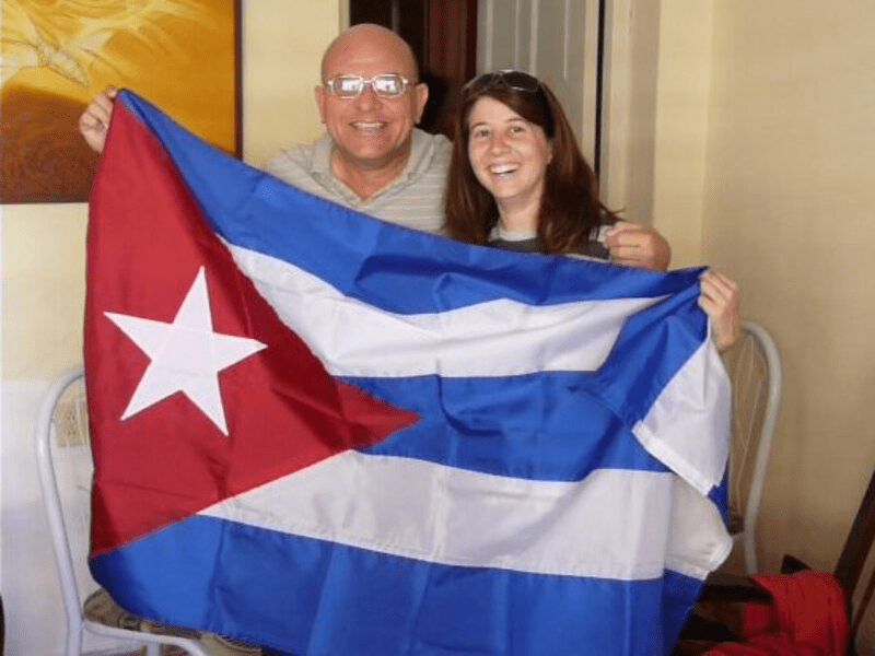 Dos personas alzando una bandera cubana.