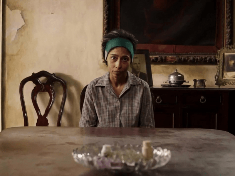 Mujer sentada de frente a una mesa.