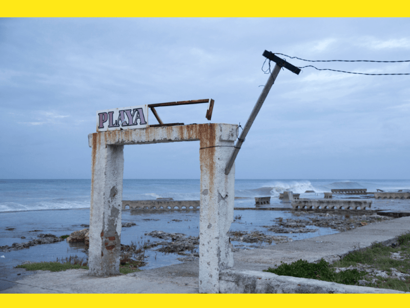Cartel con el nombre de "Playa" abandonado y corroído por el mar.