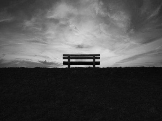 Banco vacío en un paisaje al atardecer. Blanco y negro