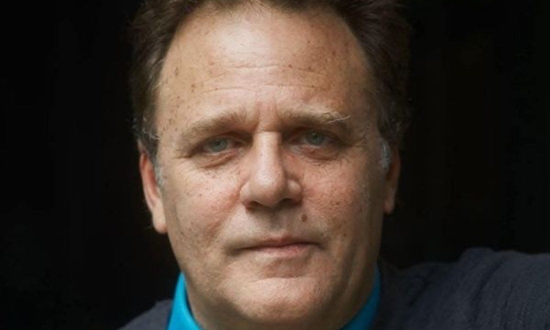 Retrato de Mauricio Rentería, actor y director de teatro, mirando a cámara, plano medio con fondo oscuro.