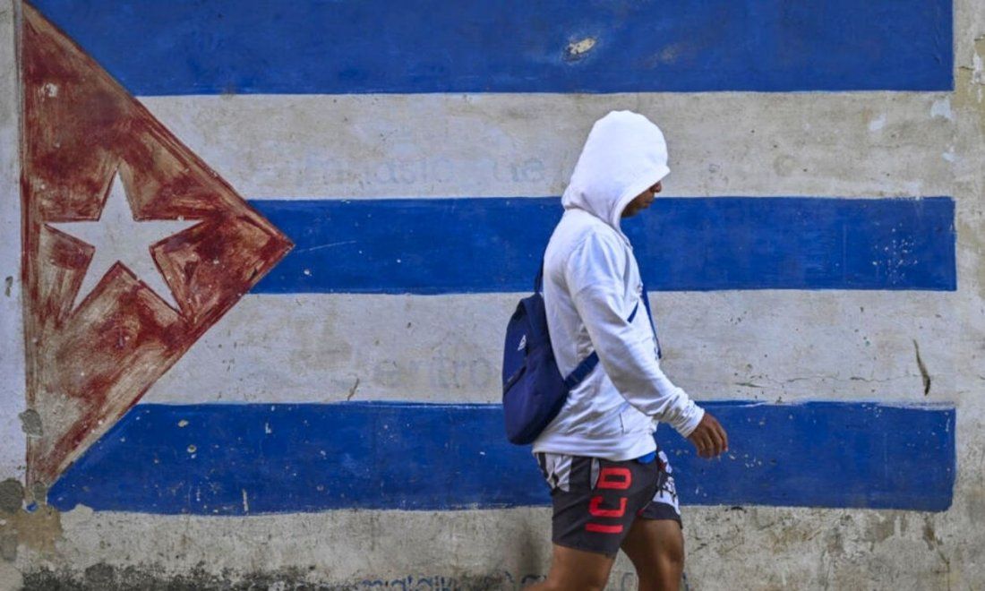 Una persona caminando frentea una bandera de Cuba pintada en un muro de La Habana el 22 de marzo de 2026. Foto de Yamil Lage (AFP).