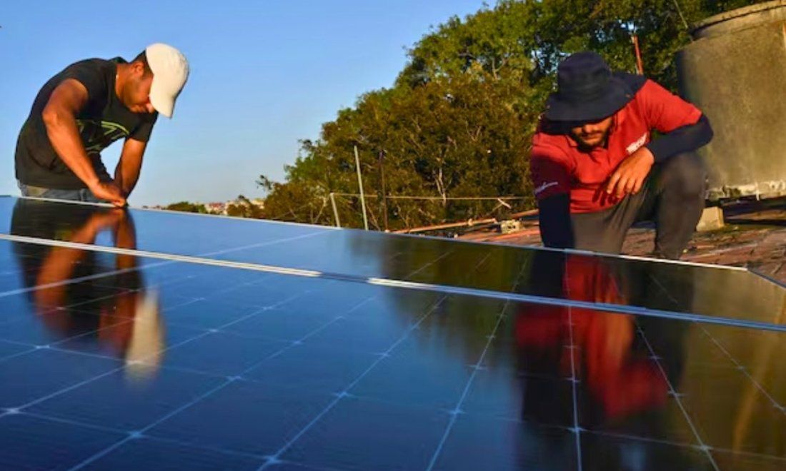 Cubanos instalando un panel solar en una vivienda en la Isla. Foto de Reuters.