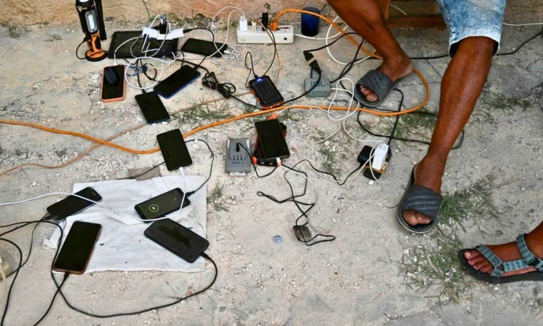 Cubanos cargando teléfonos móviles y equipos en medio de los apagones. Foto: AFP.